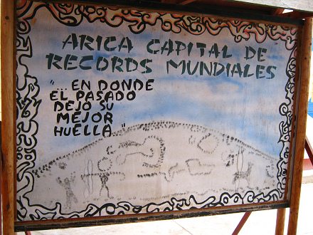 Bild mit der Angabe von Rekorden von
                          Arica: "Arica, die Hauptstadt der
                          Weltrekorde" (01) mit einer Malerei des
                          Heiligen Bergs und seinen Geoglyphen (cerro
                          Sagrado) und dem Text: "wo die
                          Vergangenheit ihre beste Spur hinterlassen
                          hat", Nahaufnahme