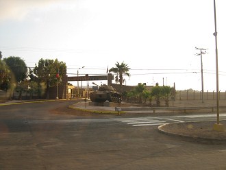 Primera brigada, la entrada con un tanque
                        como "adorno"