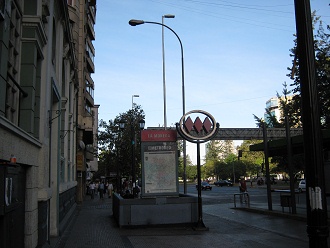 Der Eingang der U-Bahnstation
                        "Moneda" mit dem Symbol der U-Bahn von
                        Santiago mit drei roten Trapezen