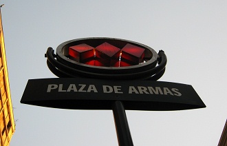 Waisenkinderstrasse (calle Hurfanos),
                          der Eingang zur U-Bahnstation
                          "Zentralplatz" (Waffenplatz, plaza
                          de Armas), das Logo der U-Bahn von Santiago de
                          Chile mit drei roten Trapezen