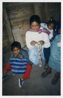 Bordadora con
pequeńo nińo en la espalda y otro nińo en el
piso Bordadora con pequeńo nińo en la espalda y
otro nińo en el piso