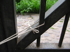 Das andere Ende des
                                Taillen-Webstuhls ist hier am Pfosten
                                befestigt