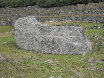 Machu Picchu, la piedra ceremonial, vista
                    lateral con una escalera al lado