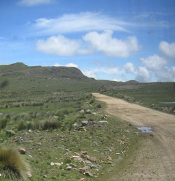 Der Feldweg mit Pfützenschlagloch und
                        Wolkenbild